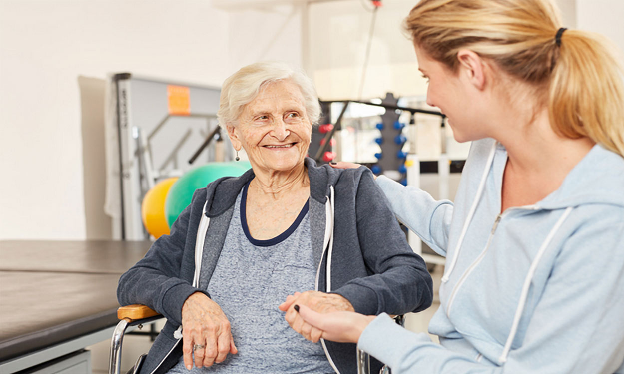 Physical therapist working with an older adult in a gym.