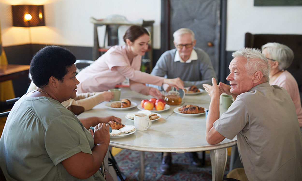 Group of older adults sharing a meal at a senior dining center.