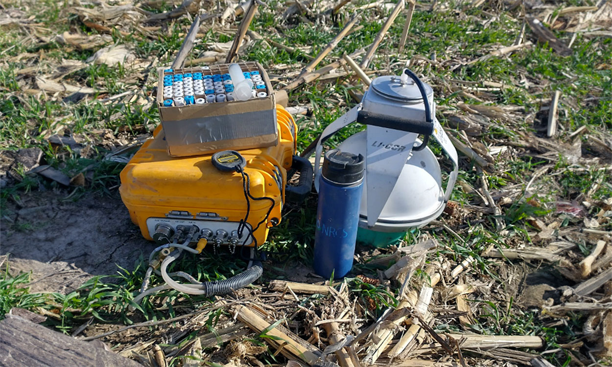 Equipment used to measure soil gas emissions resting in a field.
