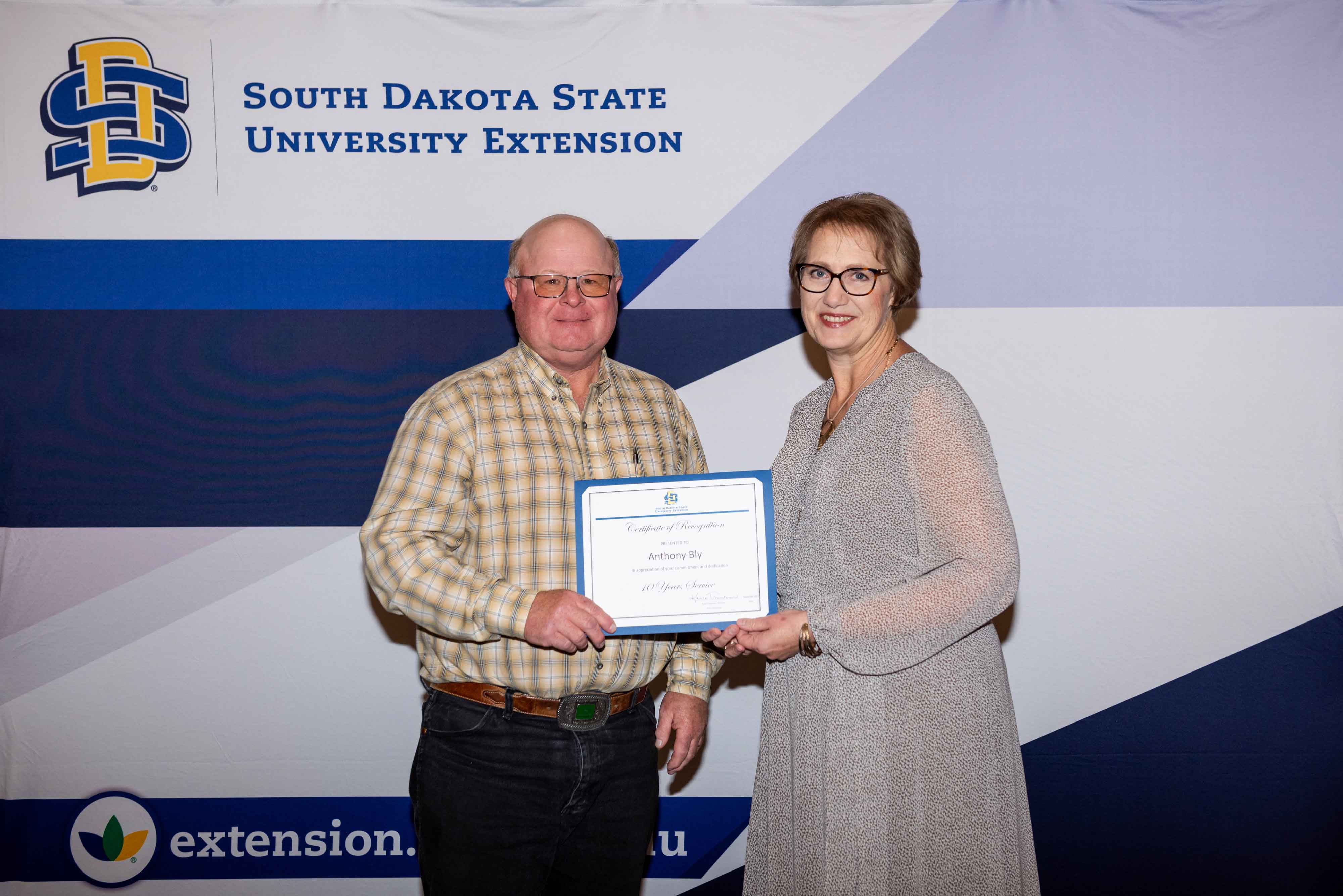 Anthony Bly receives a certificate for 10 years of service from SDSU Extension Director Karla Trautman