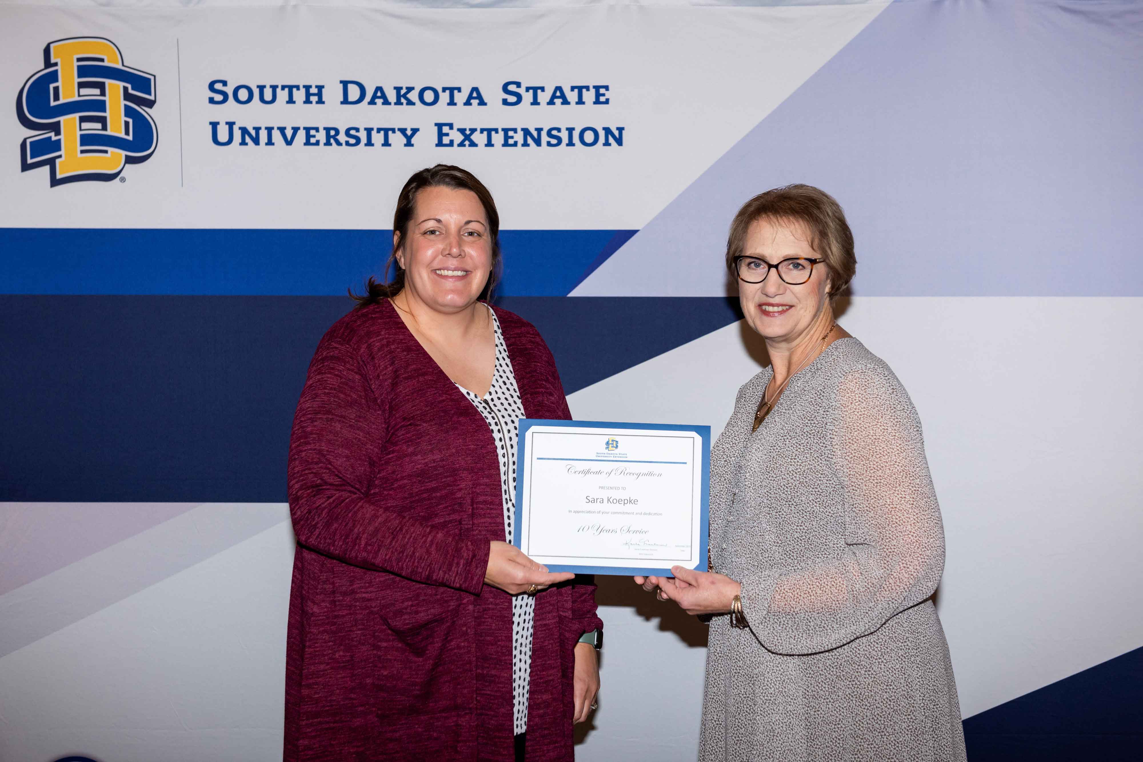 Sara Koekpe receives a certificate for 10 years of service from Karla Trautman