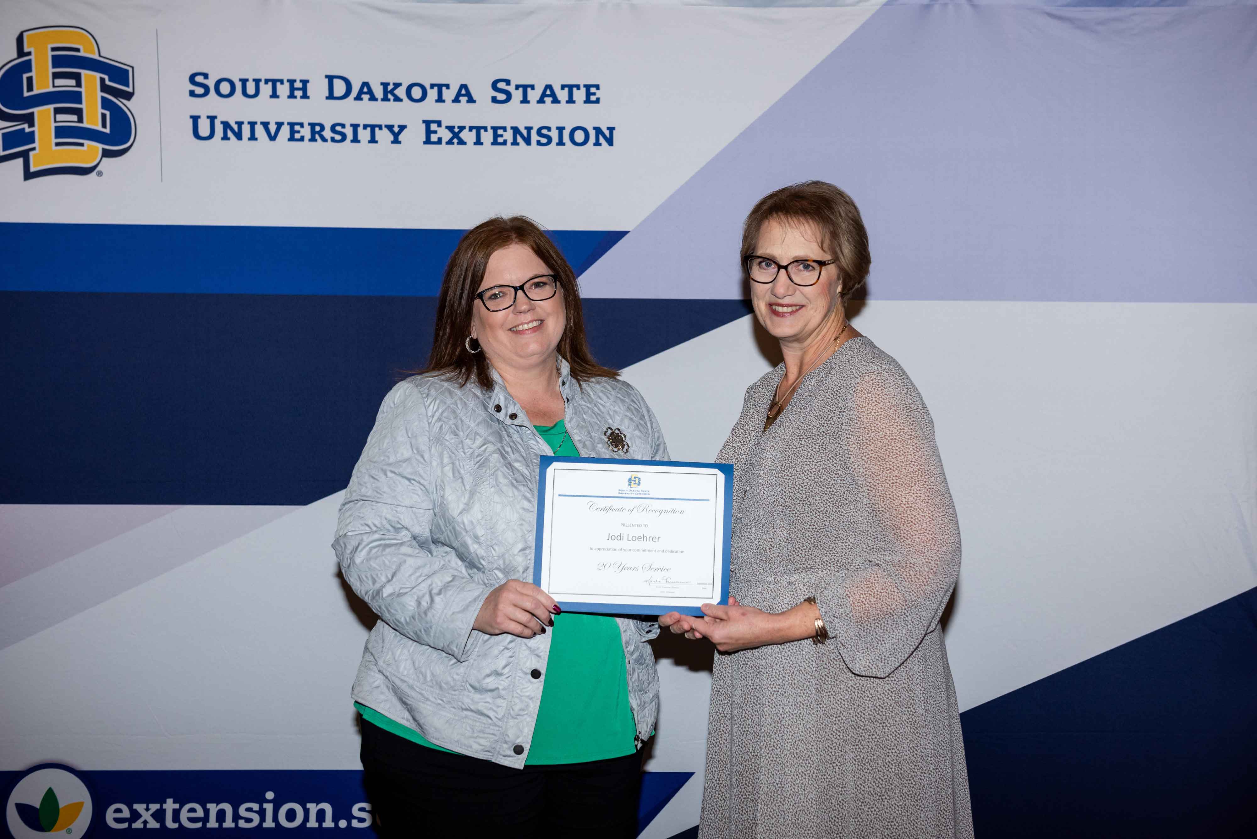 Jodi Loehrer receives a certificate for 20 years of service from Karla Trautman
