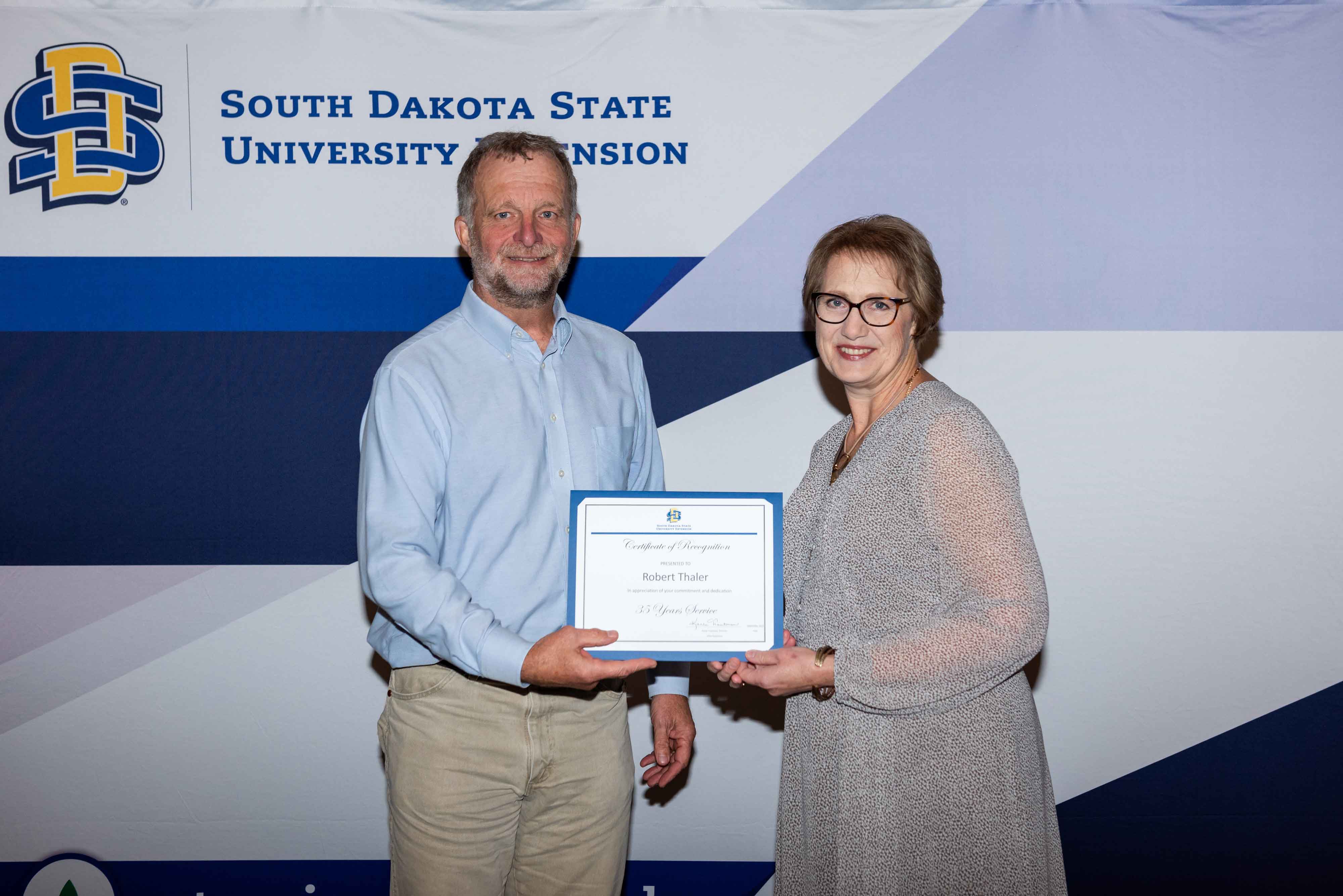 Bob Thaler smiles as he receives his certificate for 35 years with SDSU from Karla Trautman