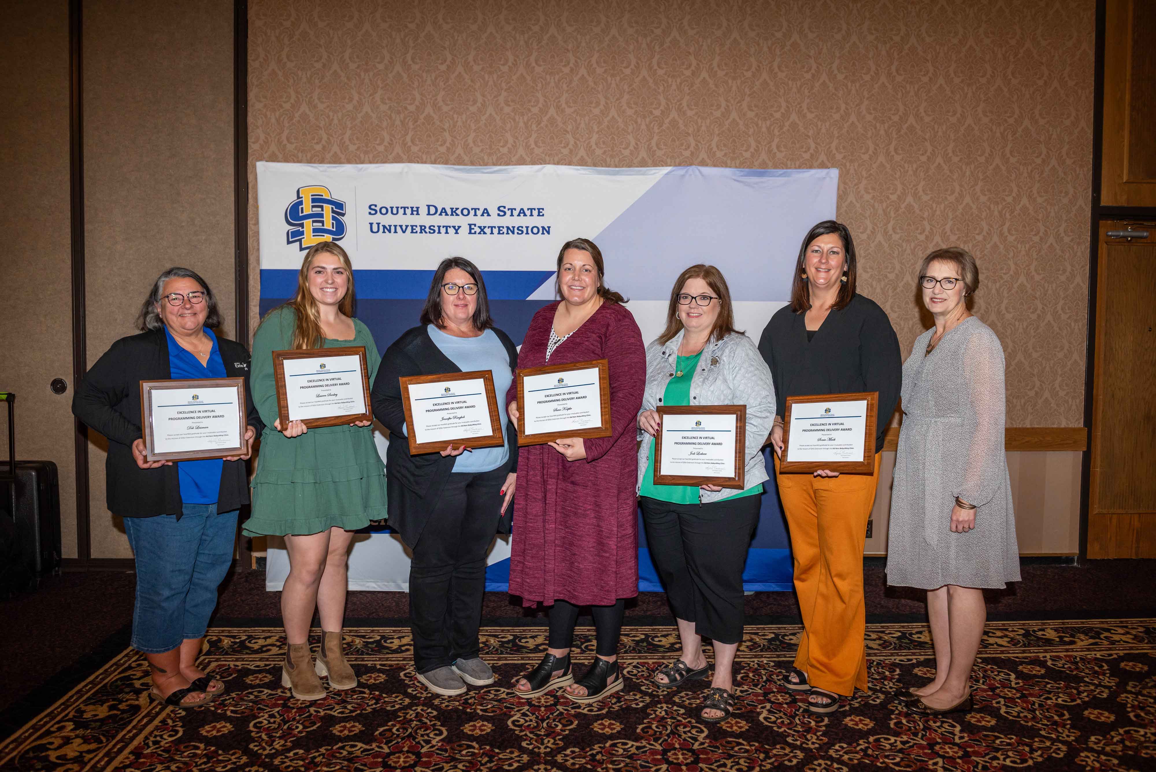SDSU Extension professionals smile at the camera displaying their Excellence in Virtual Program Delivery Award certificates