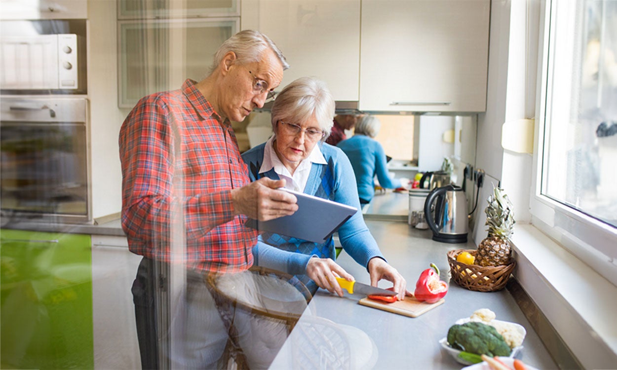 Older couple preparing a healthy meal following an online recipe.