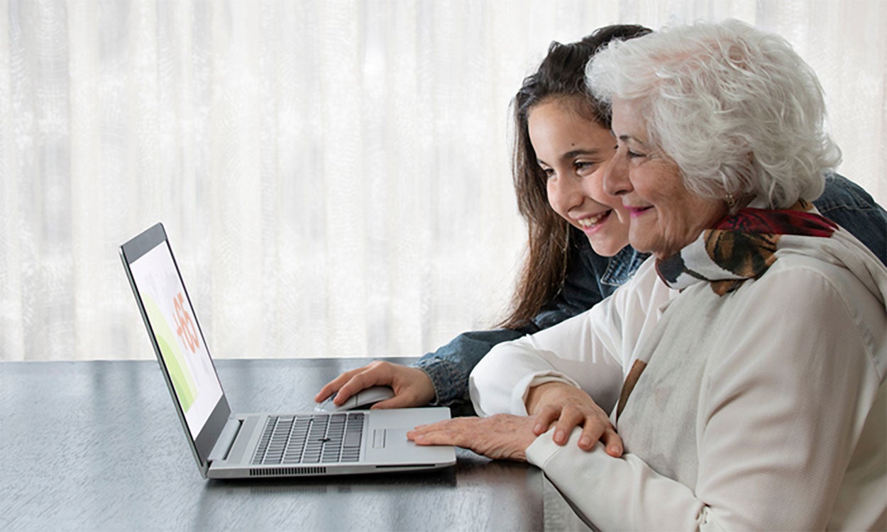 Granddaughter reviewing information on a laptop with her grandmother.