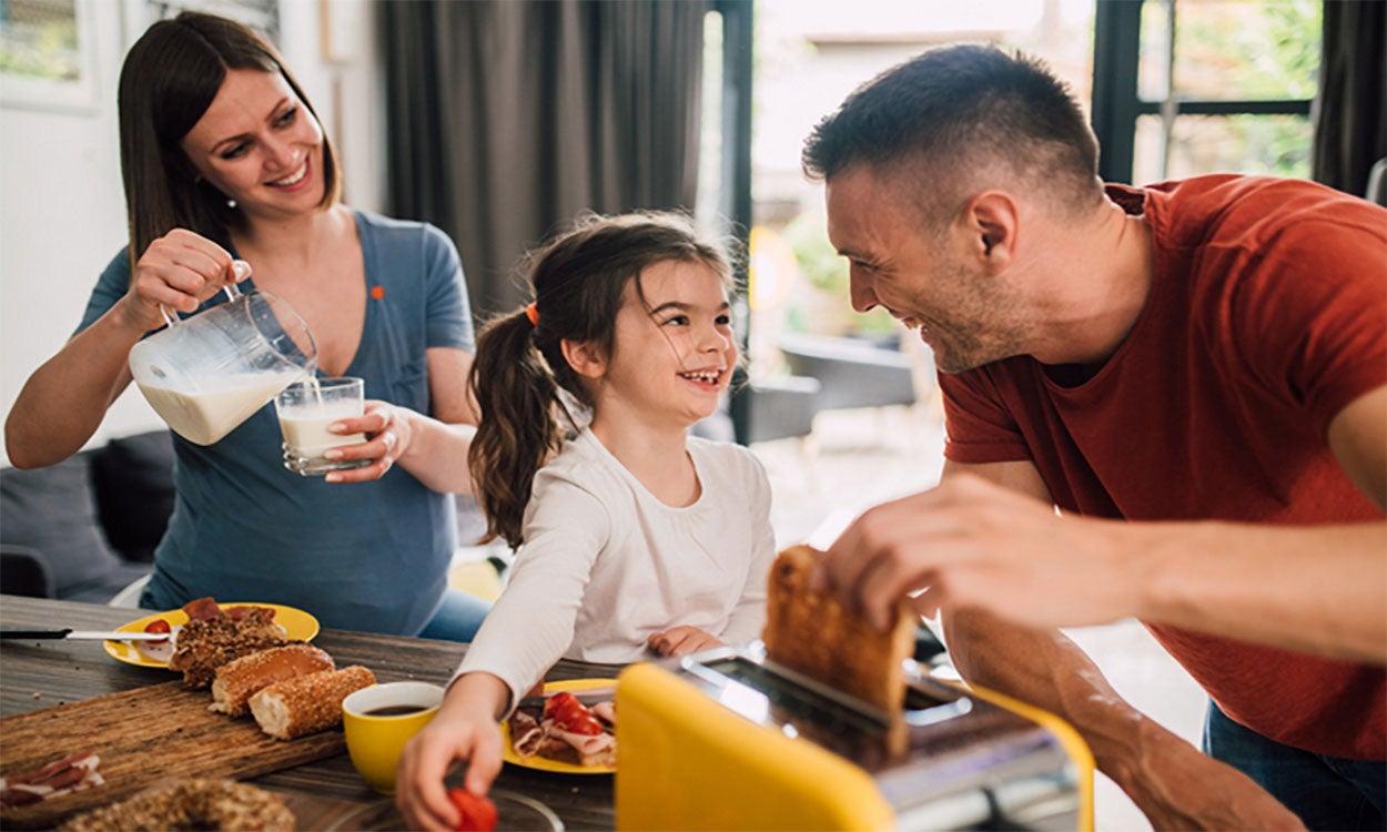 Mother, father, and daughter preparing breakfast together.
