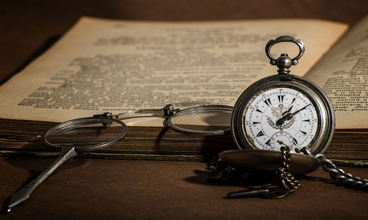 Glasses and pocket watch beside an open journal.