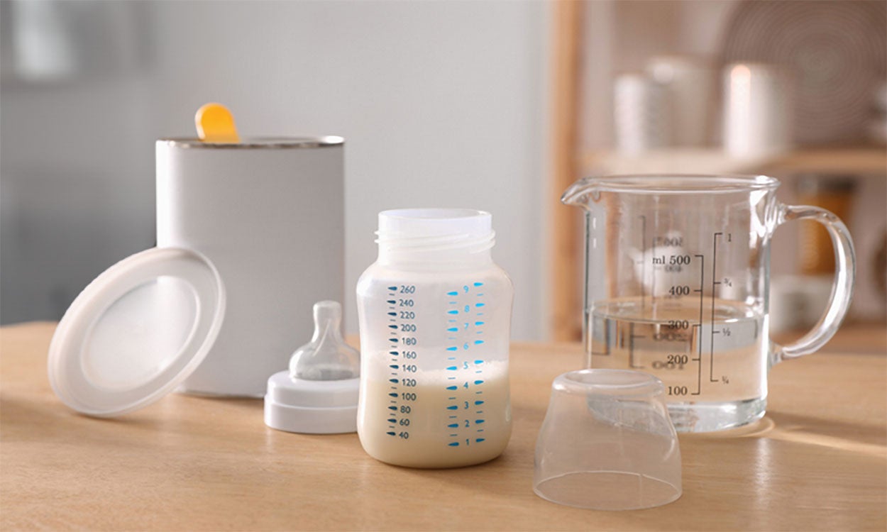 Infant formula, bottle, distilled water, and can of formula on a kitchen counter.