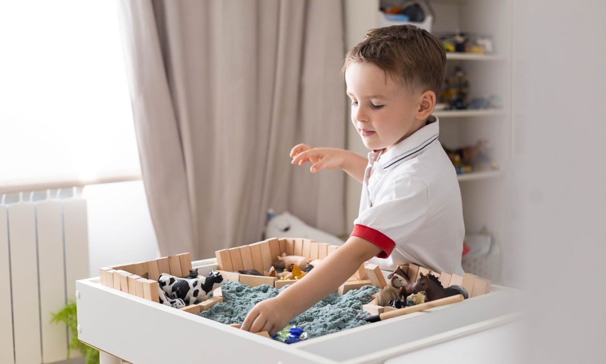 Child exploring a variety of textures in a sensory play box.