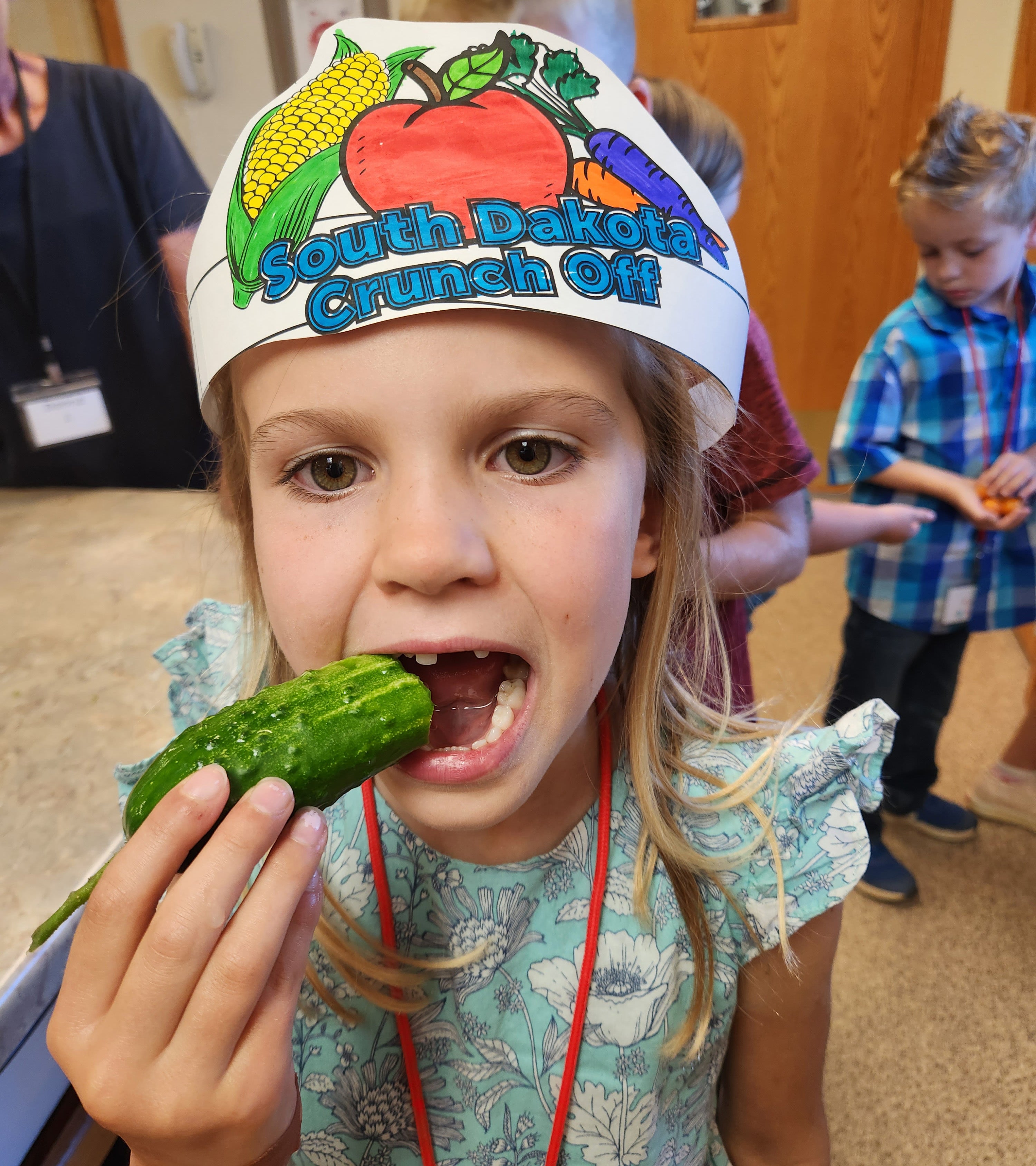 Young girl wearing a South Dakota Crunch Off crown and biting into a cucumber