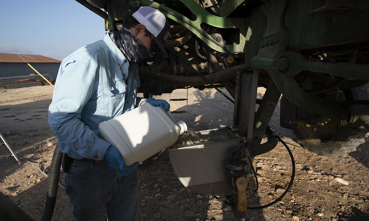 Producer loading pesticide into a sprayer tank.