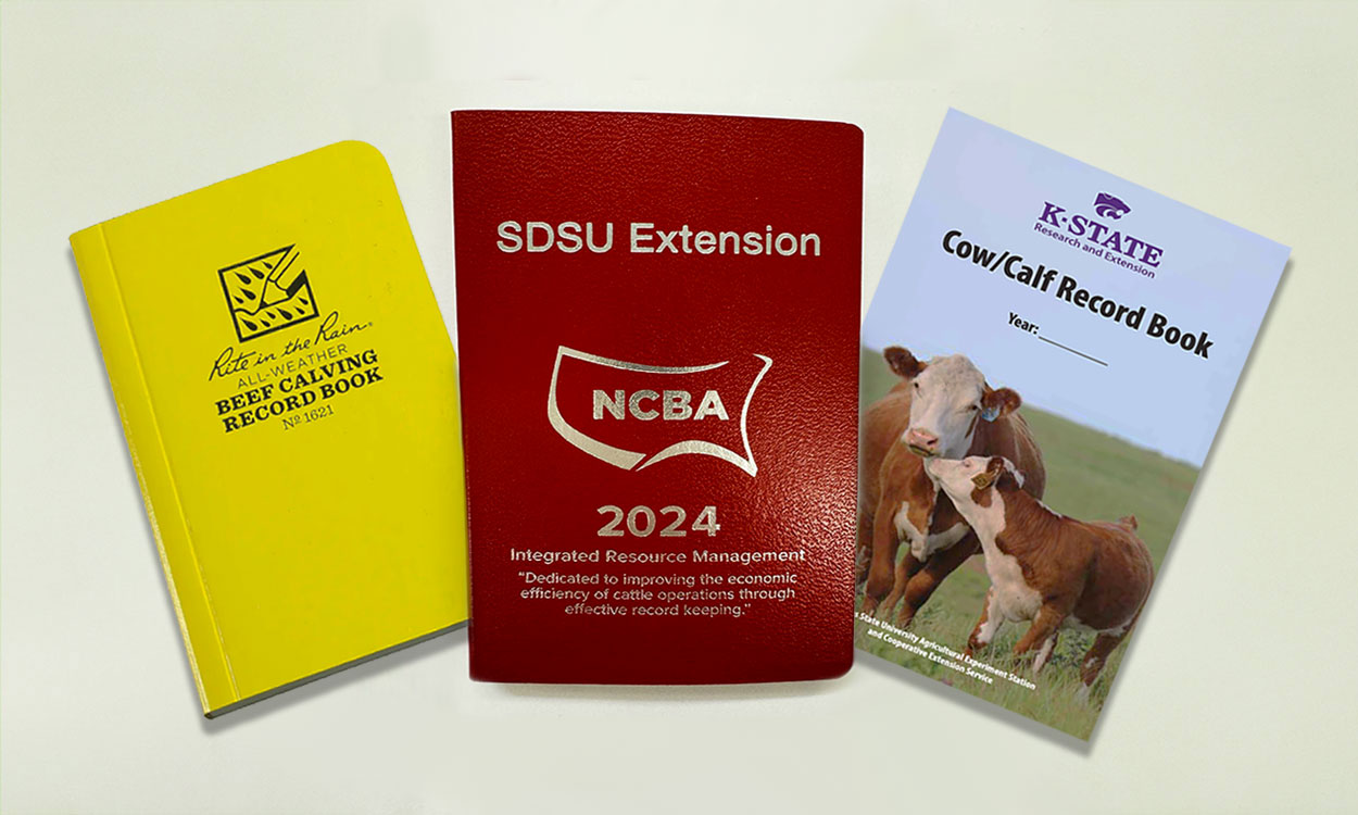 Three calving books on display: Rite in the Rain book, SDSU Extension IRM Redbook, and the K-State cow/calf record book.