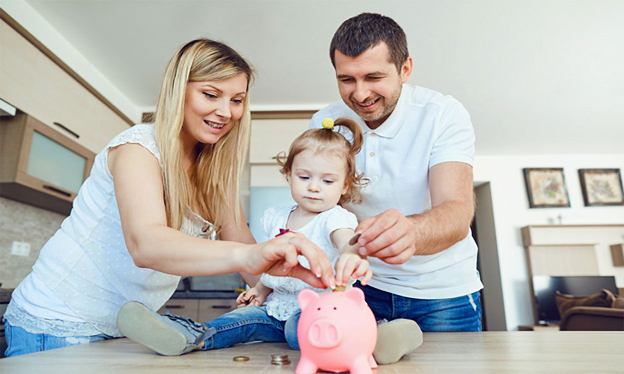 Mother, father, and daughter putting coins in a piggy bank.
