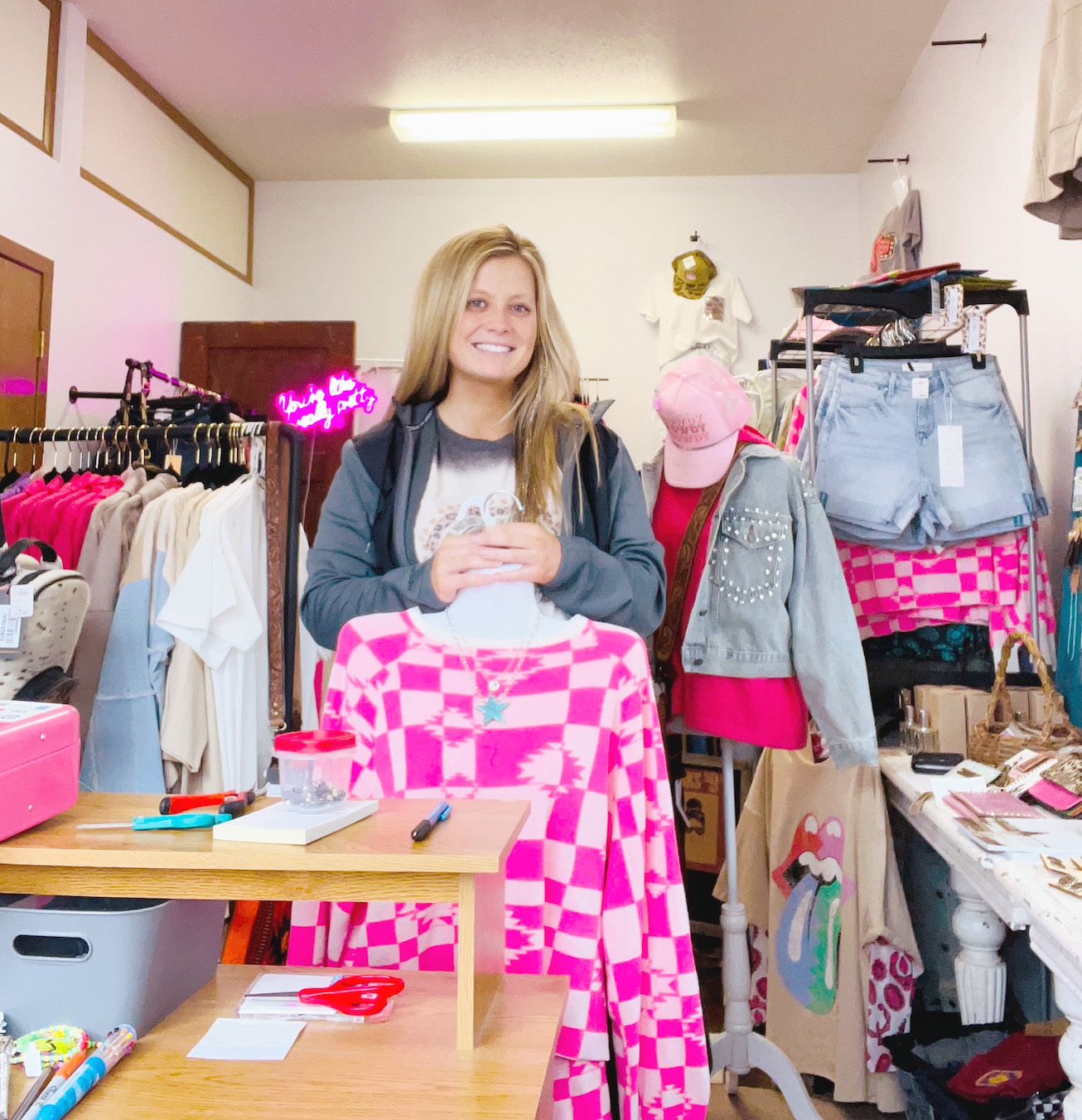 A woman stands in a clothing store behind a pink shirt with geometric patterns