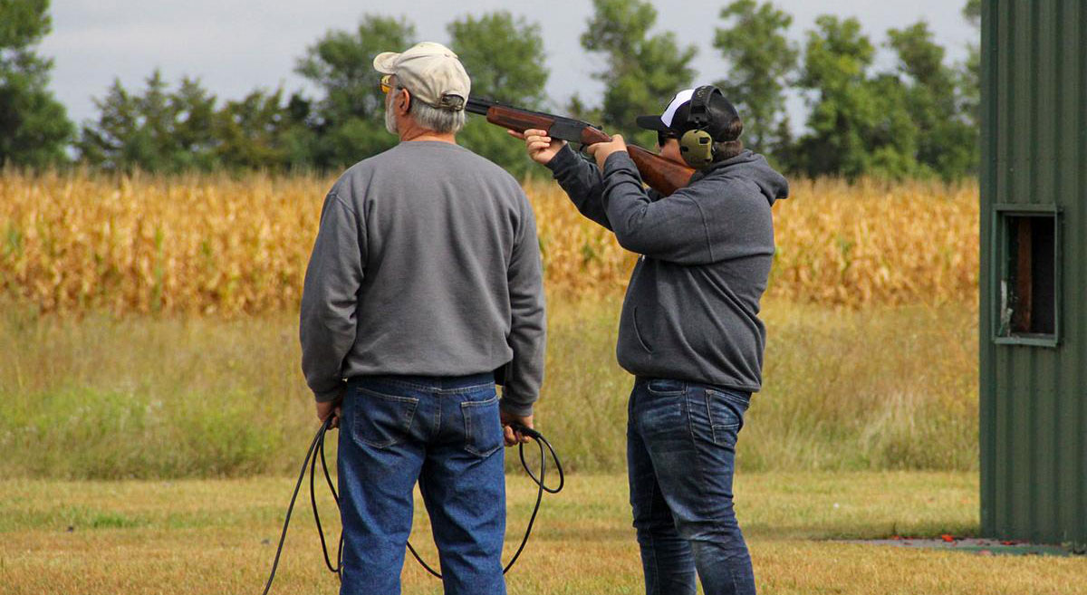4-H shooting sports coach and youth at a trap shooting range.