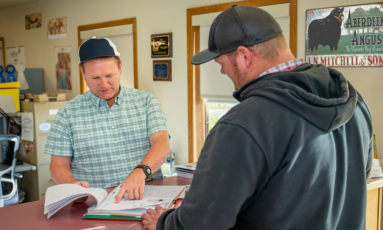 Two ranchers reviewing a checklist in a farm office.