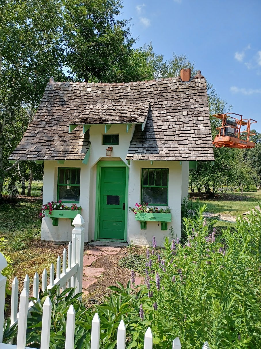 a small cottage with a green door and weathered shingles