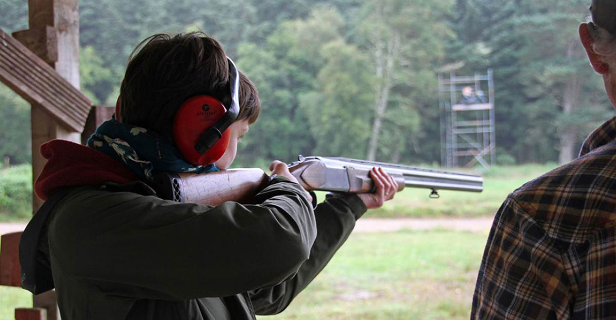 a young man practicing shooting with a shotgun instructor
