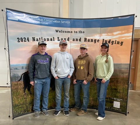 Four people stand in front of a backdrop that says "Welcome to the 2024 Land and Range judging"