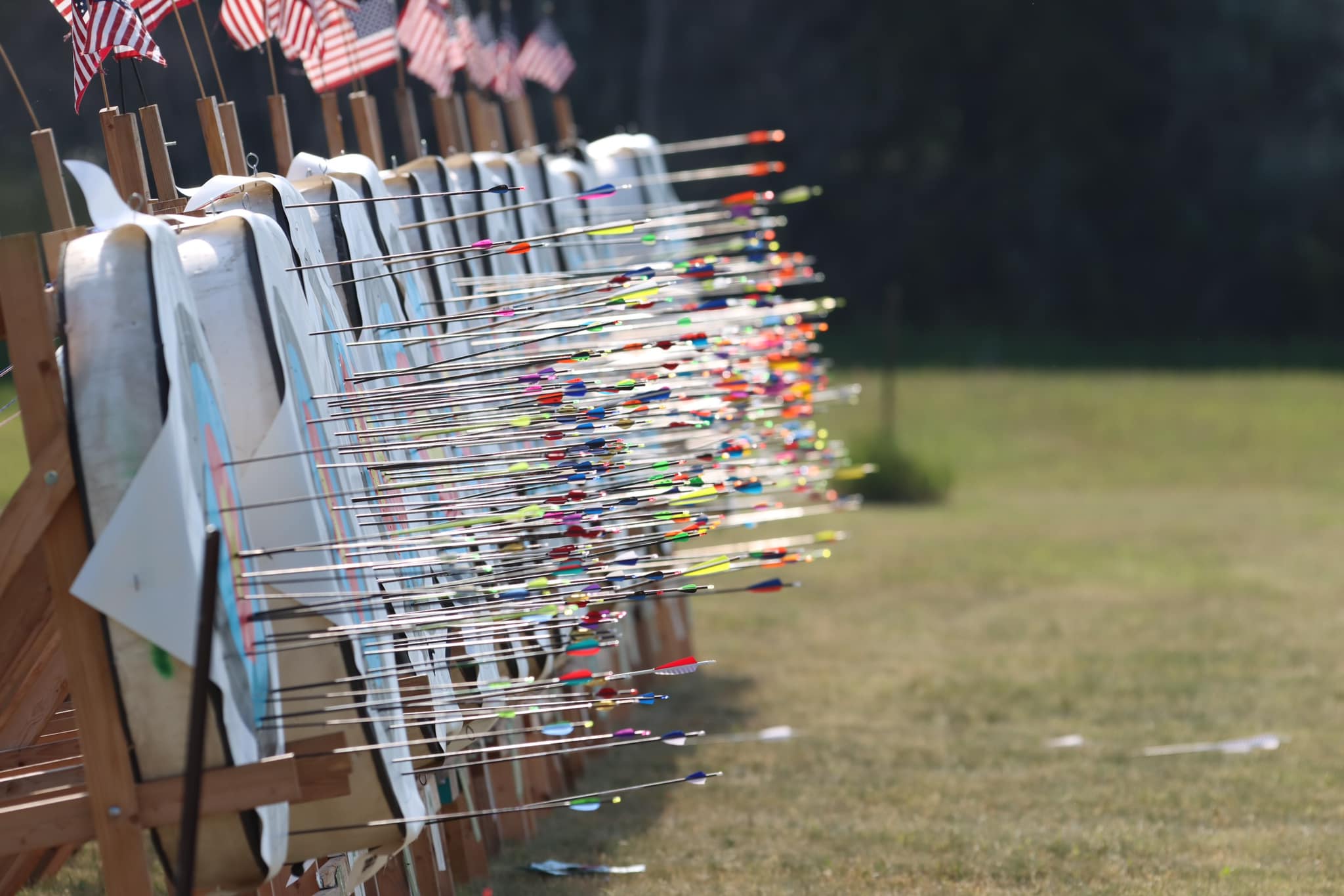 A row of targets is full of arrows in an outdoor field