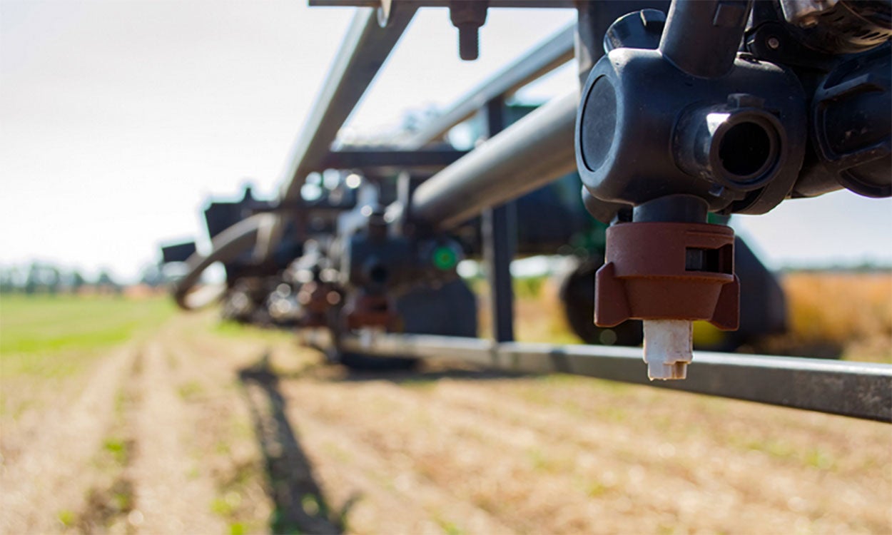 Nozzle on a boom sprayer in a crop field.