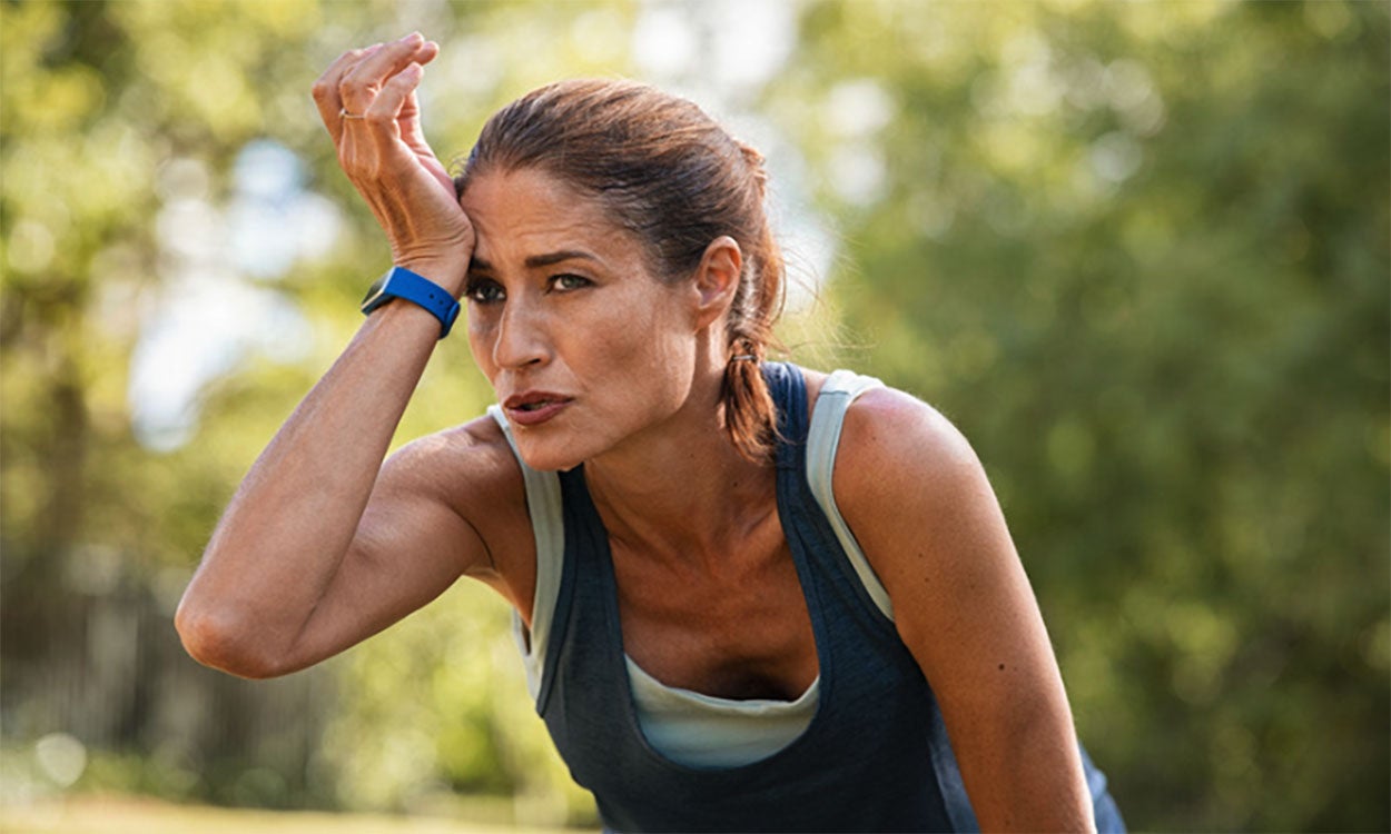 Woman pausing to catch her breath while exercising outdoors in the summer heat.