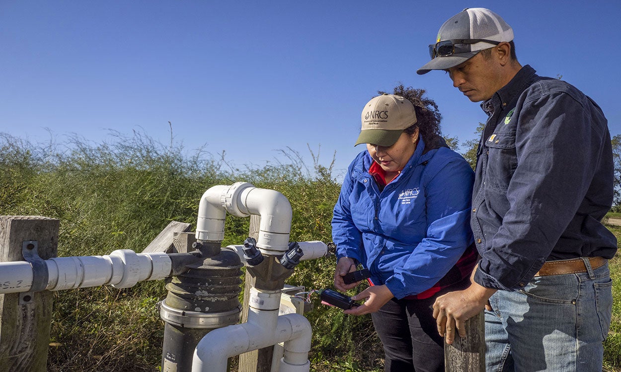 Producers examining a computer sensor at a precision watering station.