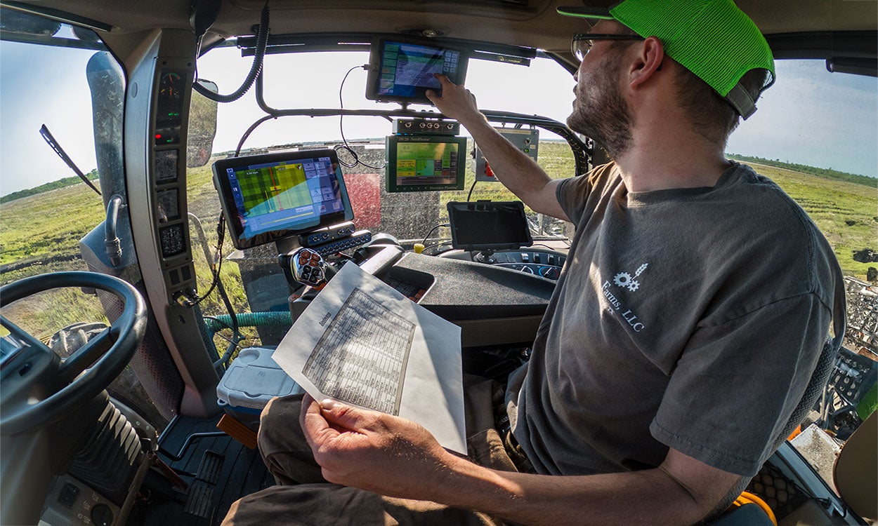Producer analyzing data on a series of screens inside a tractor equipped for precision agriculture.