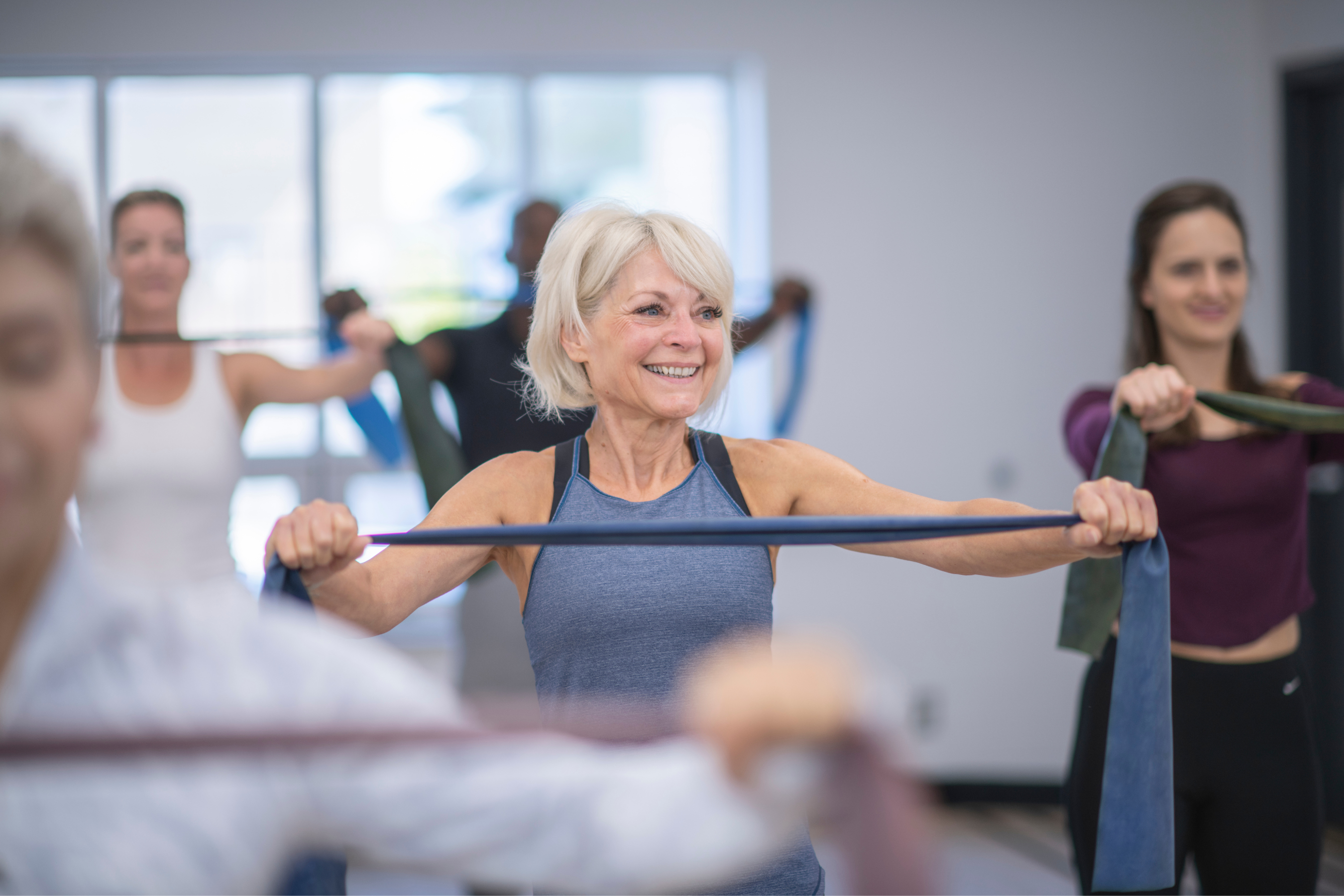older adult in a work out class using a resistance band.