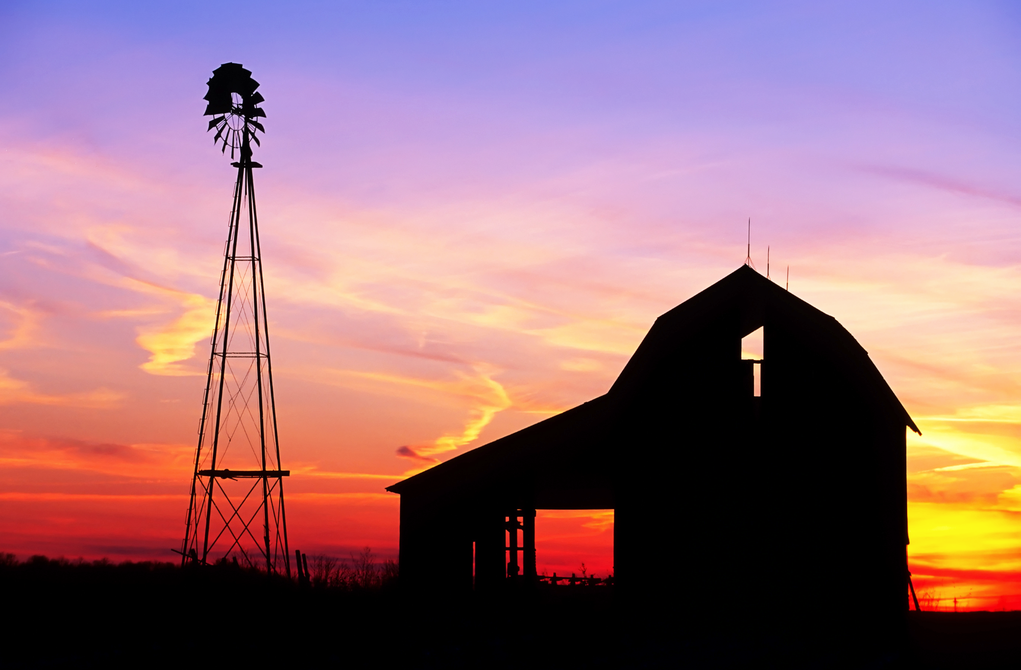 Old barn and windmill with the sunset in the background