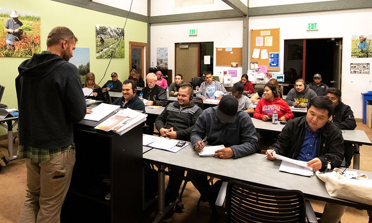 Farm manager conducting a training session with staff in a small classroom.