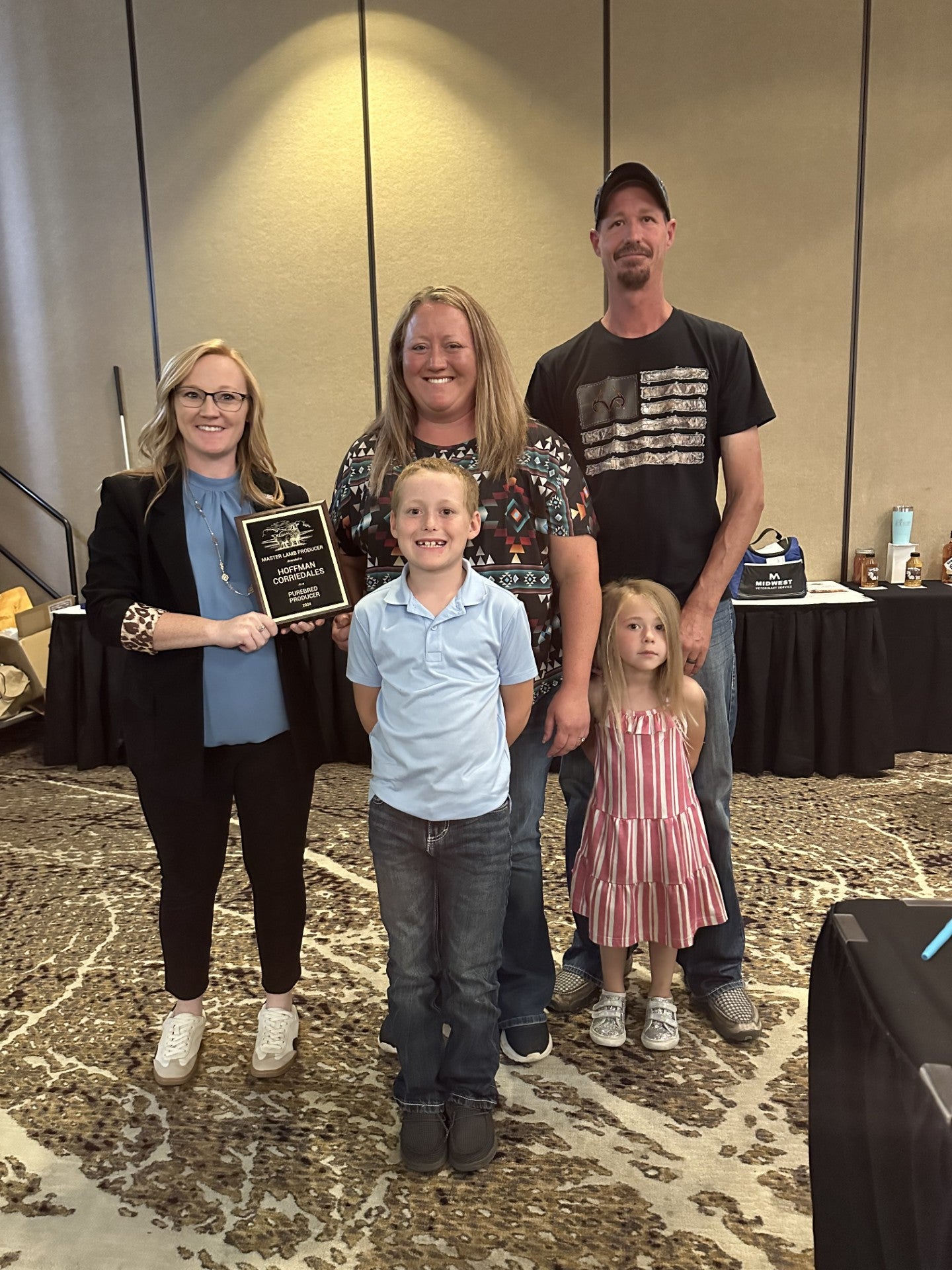 A family of four is presented a plaque by a woman in professional dress