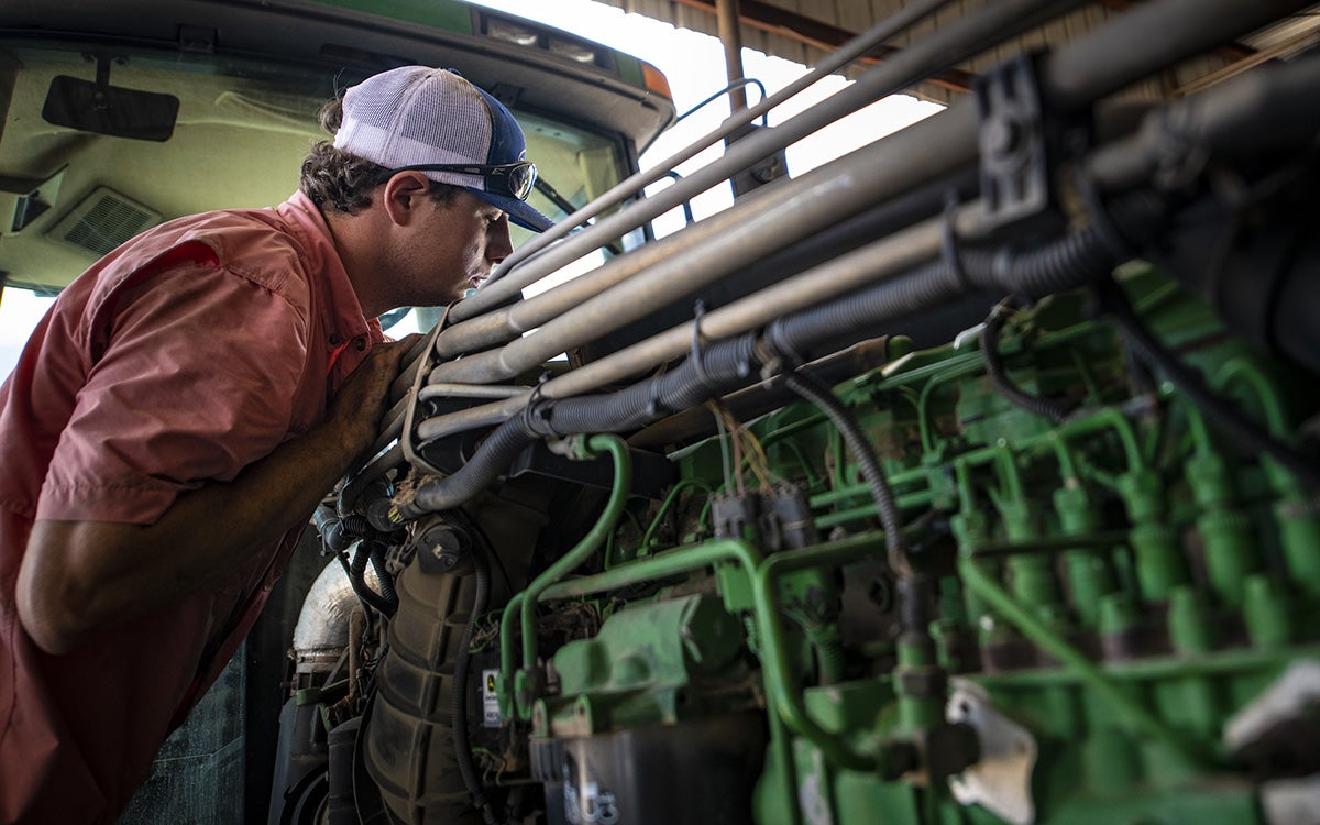 Male producer inspecting interior mechanical components of a large tractor.