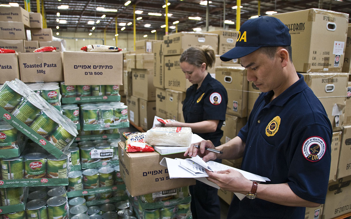 FDA agents inspecting food in a warehouse.