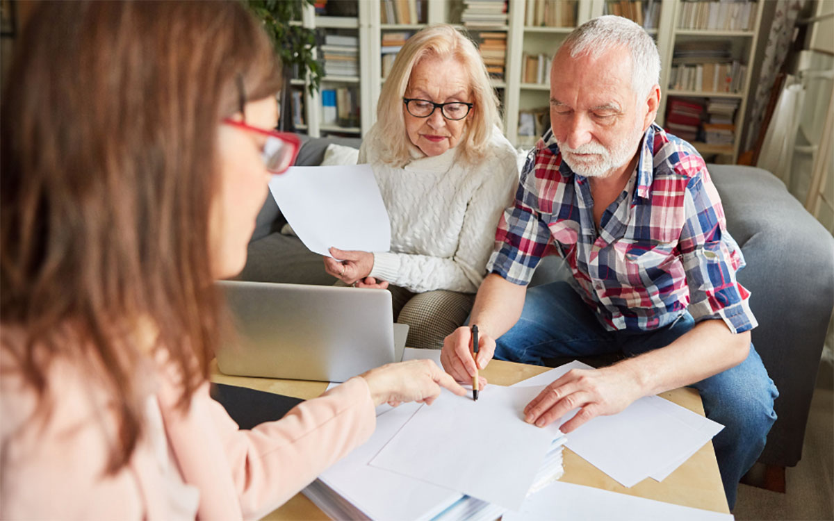 An older couple reviewing paperwork with a financial planner.
