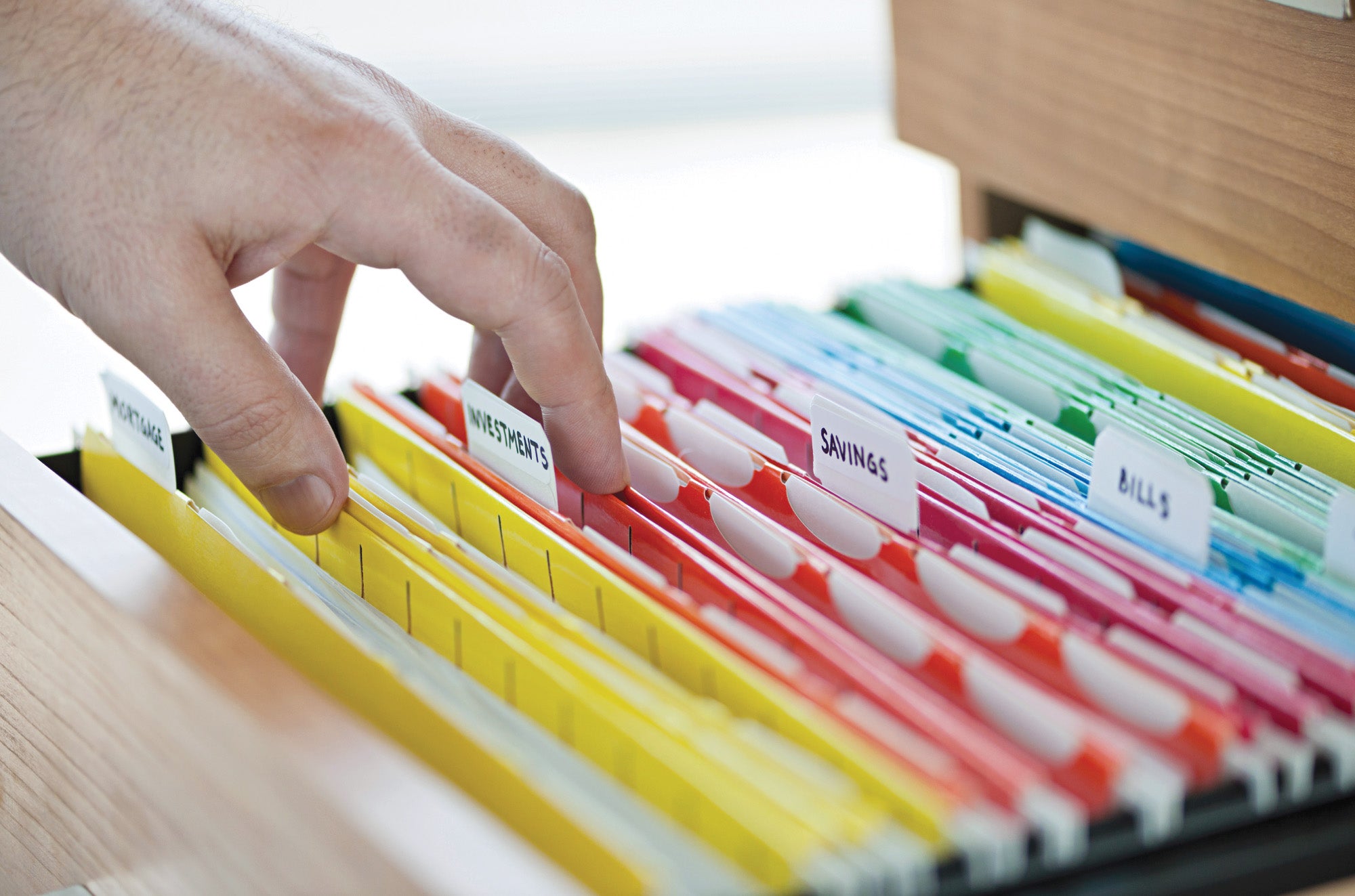 A hand picking a file in a file cabinet