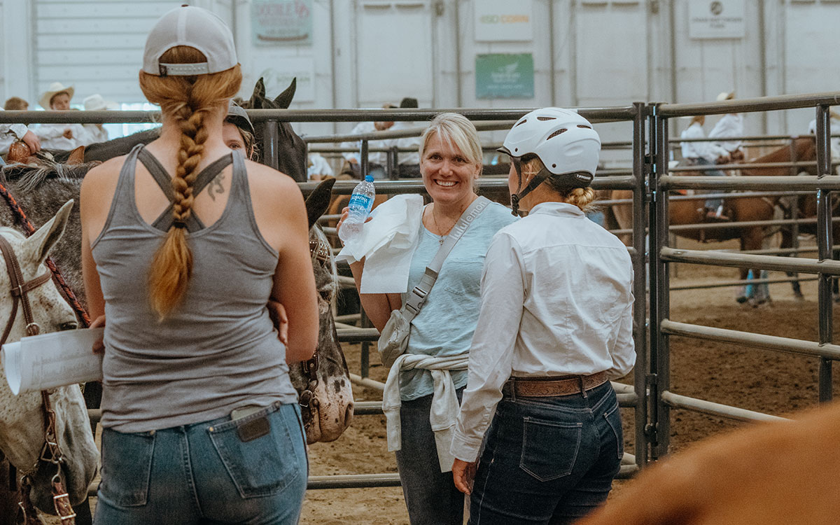 4-H horse show participants conversing in an arena.