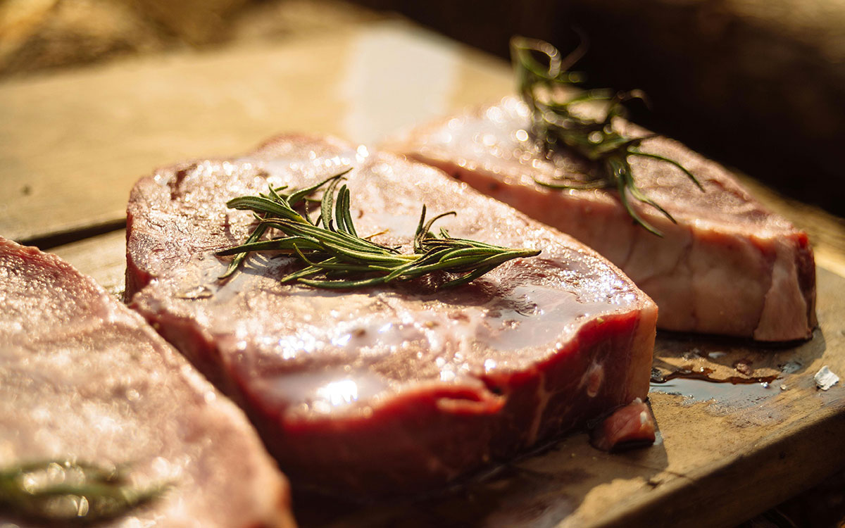 Steak cuts with rosemary on a cutting board.