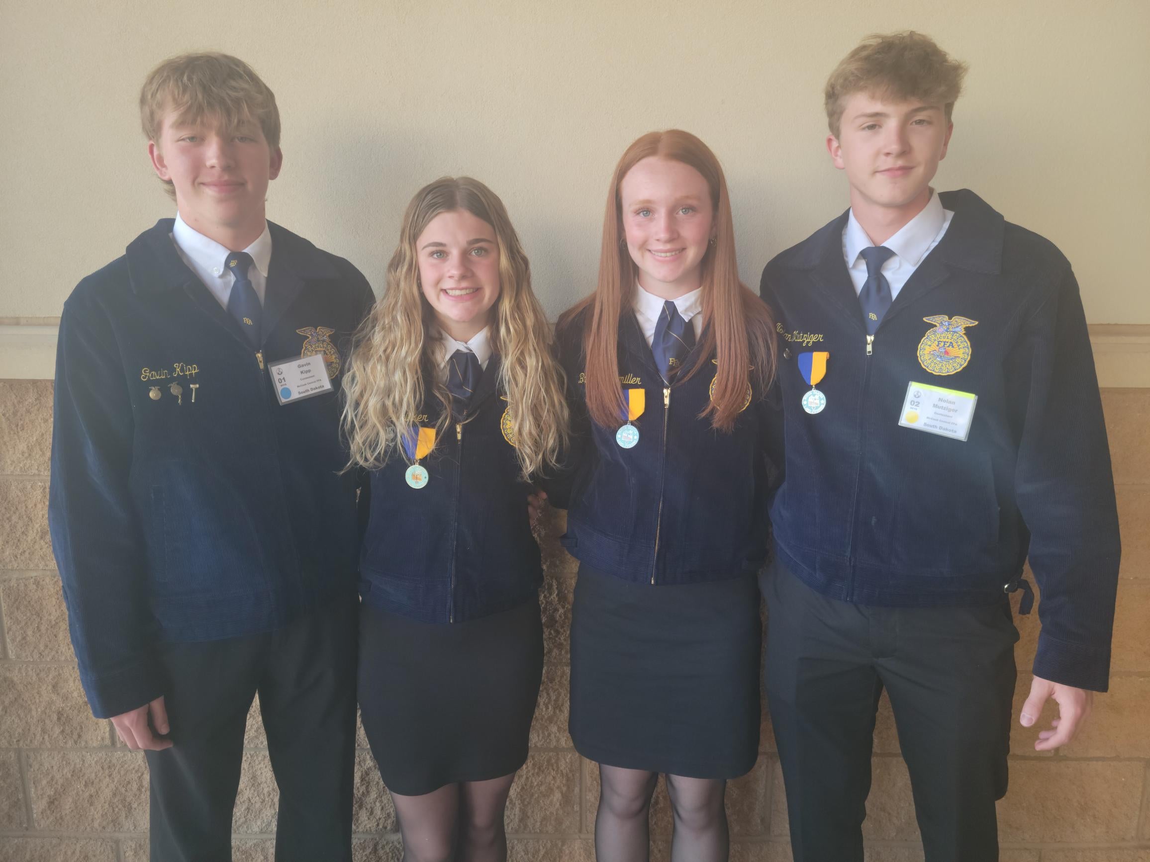 Four youth in FFA jackets stand for a team photo