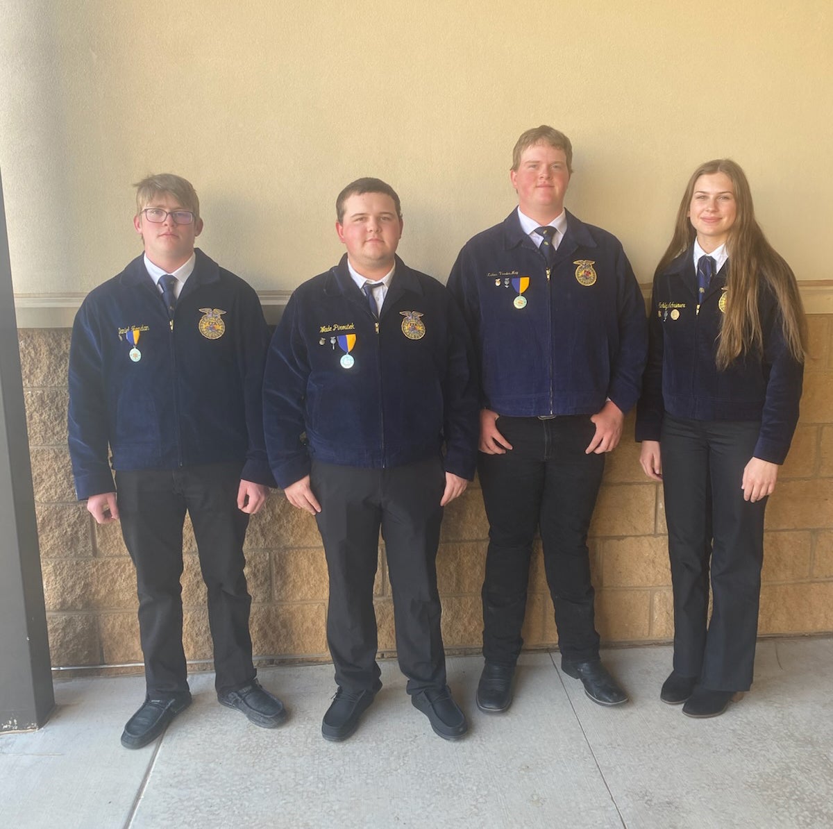 Four youth in matching blue FFA jackets pose for a team photo