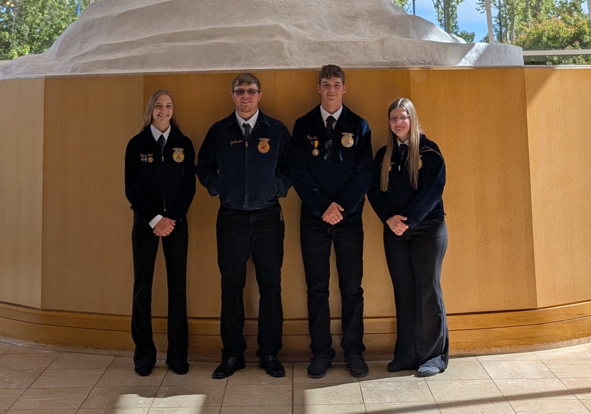Four youth in FFA jackets smile for a team photo