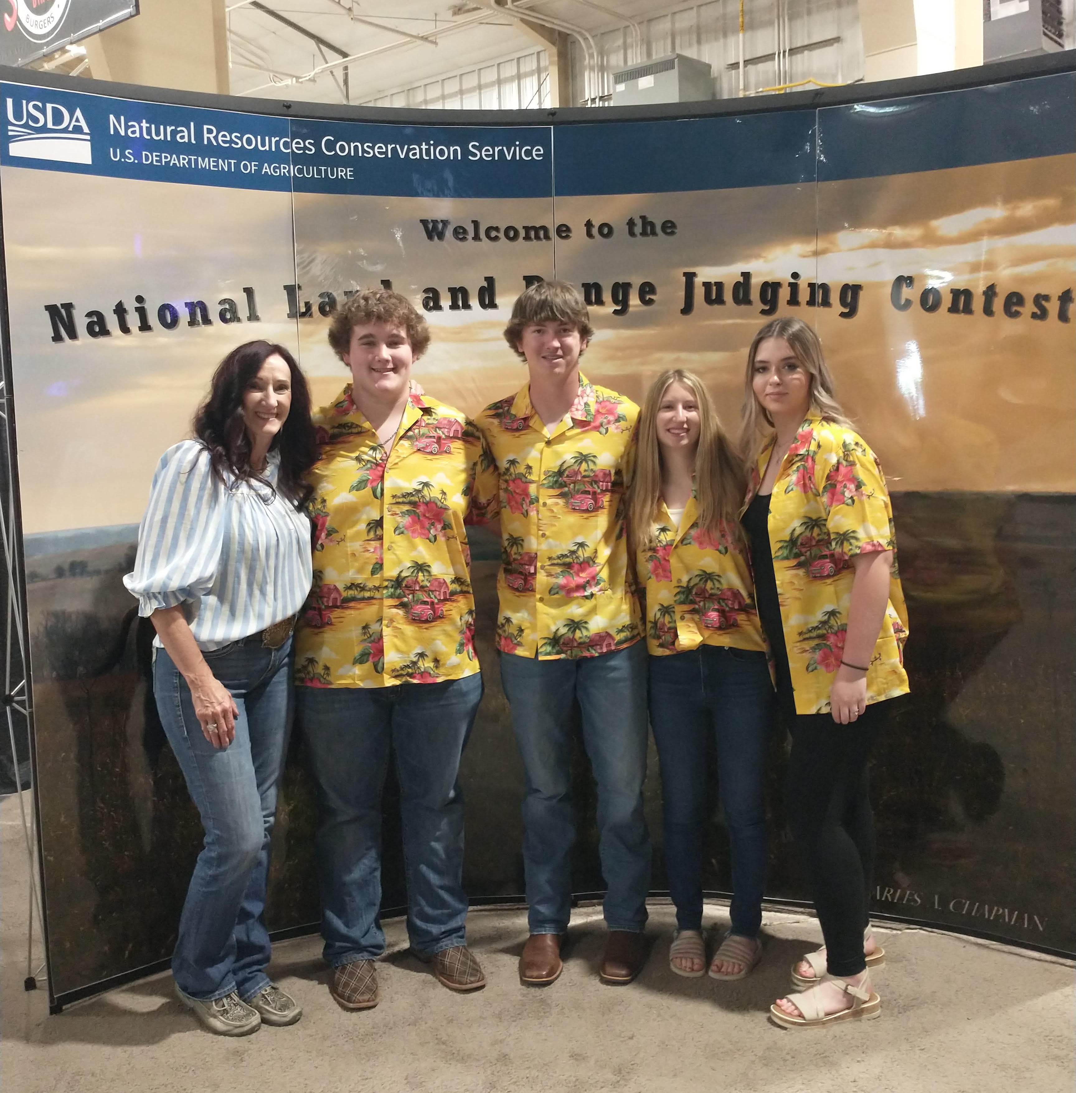 four youth in matching Hawaiian shirts smile with their coach for a team photo
