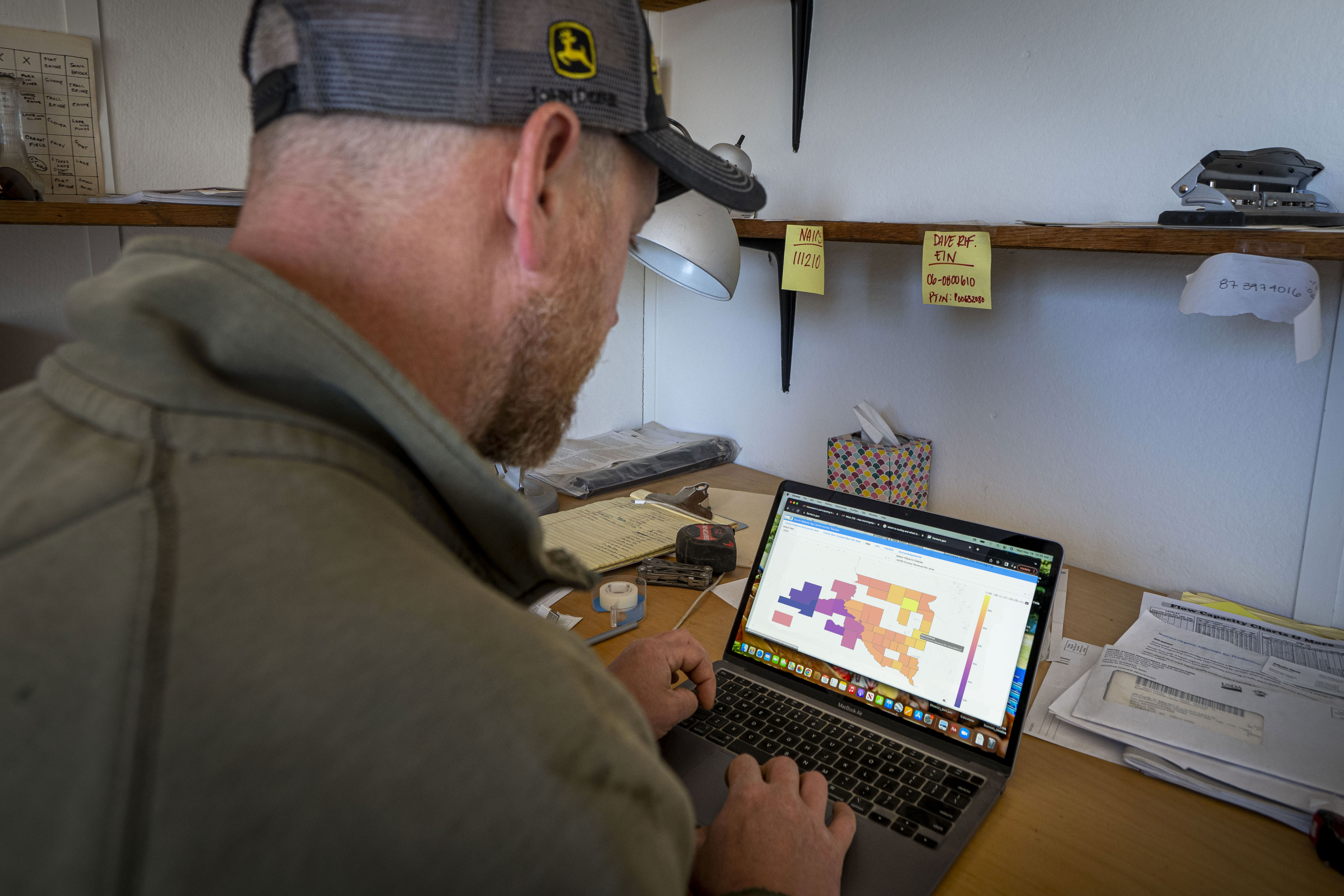 Landowner viewing information on a laptop computer in a farm office.