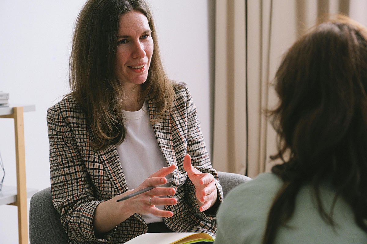 A therapist sitting with notebook and talking with a client.