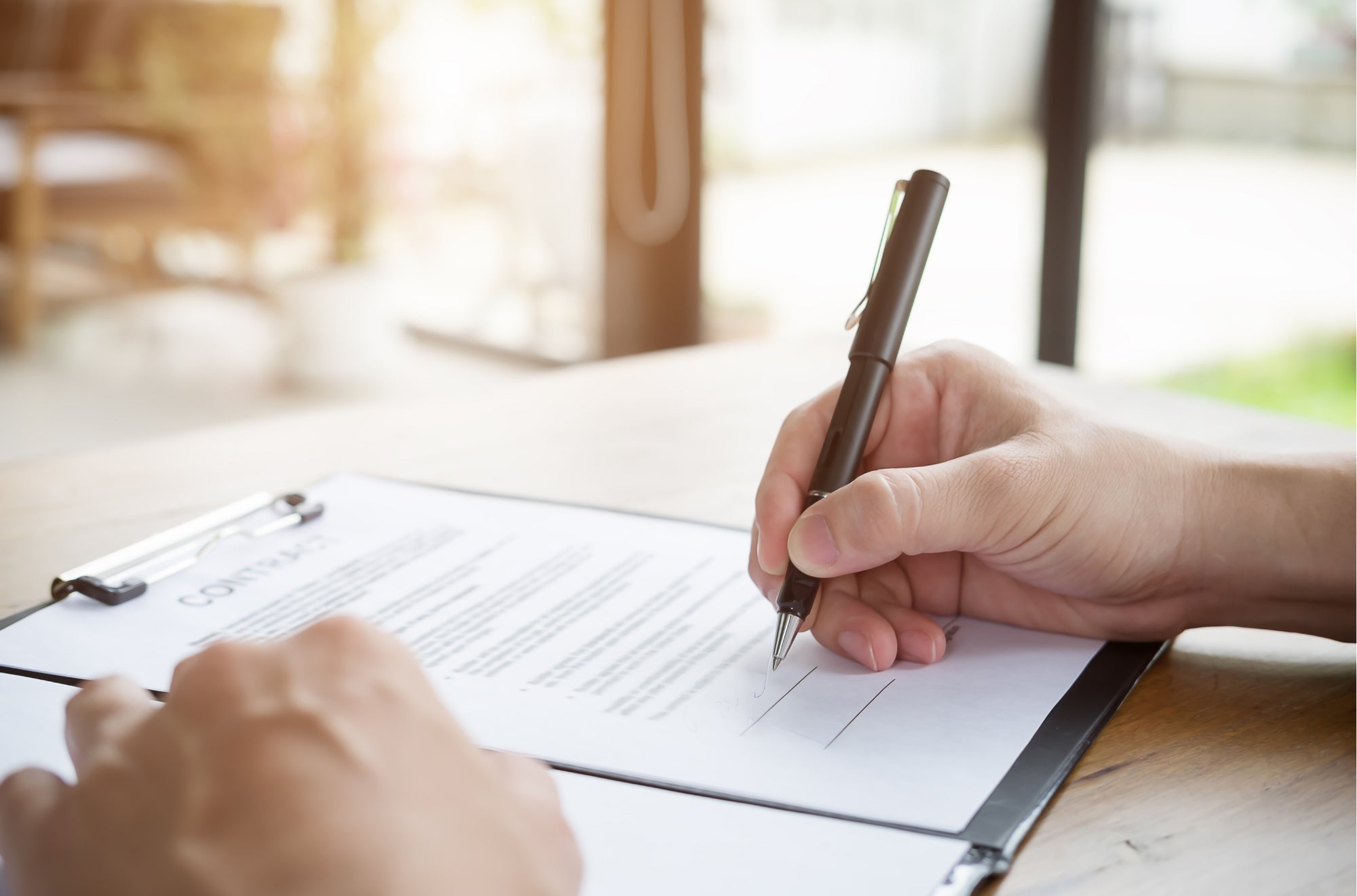 Person signing contract Person signing a contract with a black pen