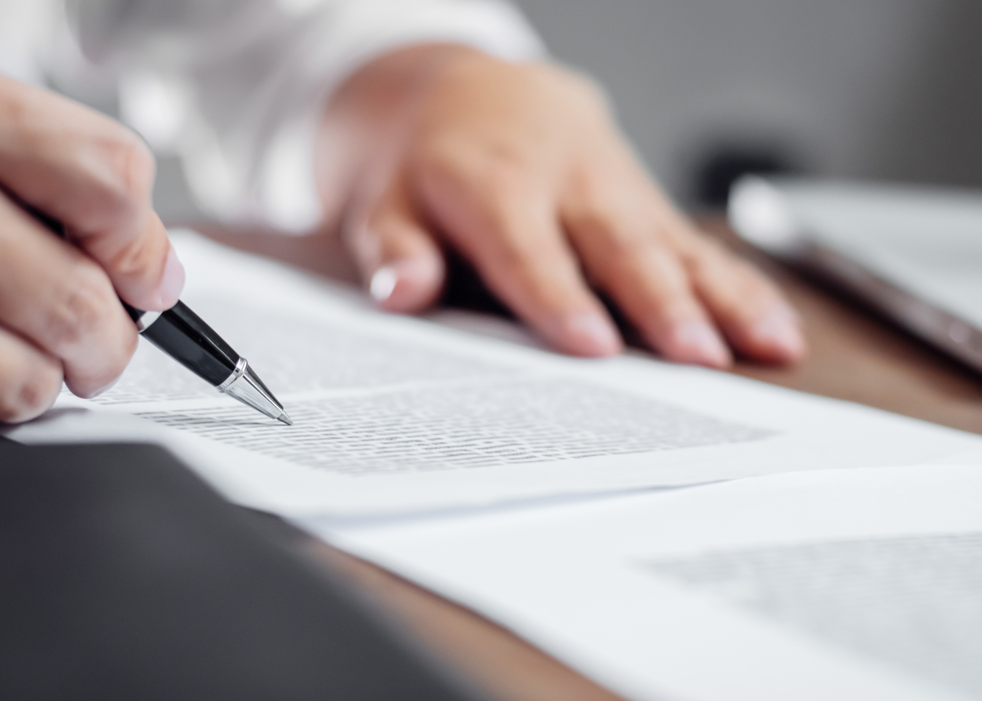 Hands reviewing a document and pointing to a certain section with a pen