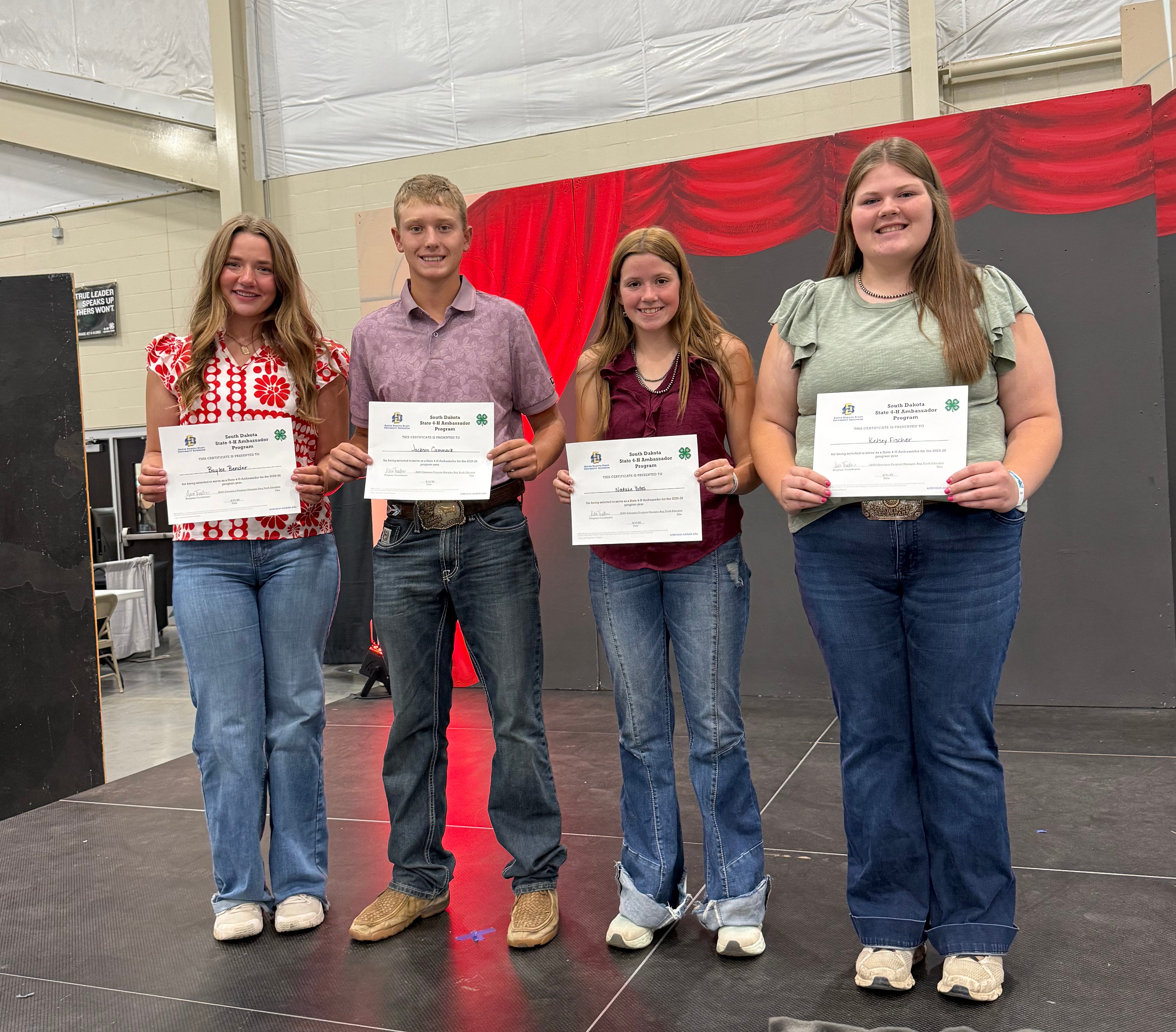 Four youth smile with certificates