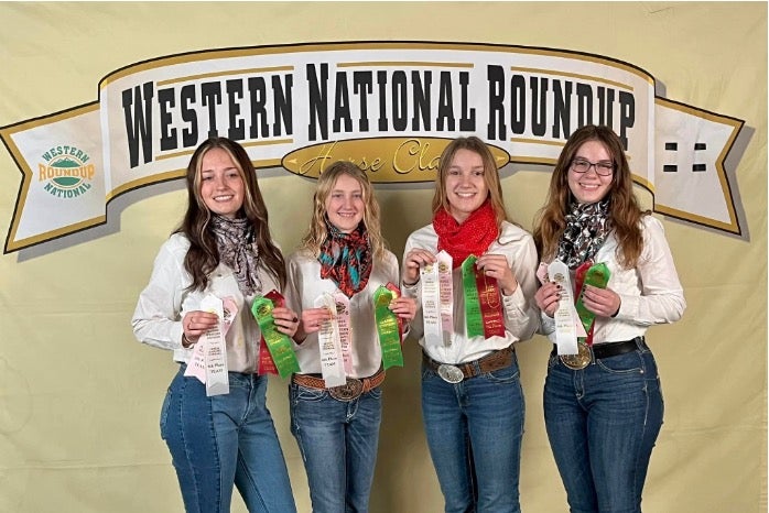 The horse judging team smiles at the camera with their ribbons