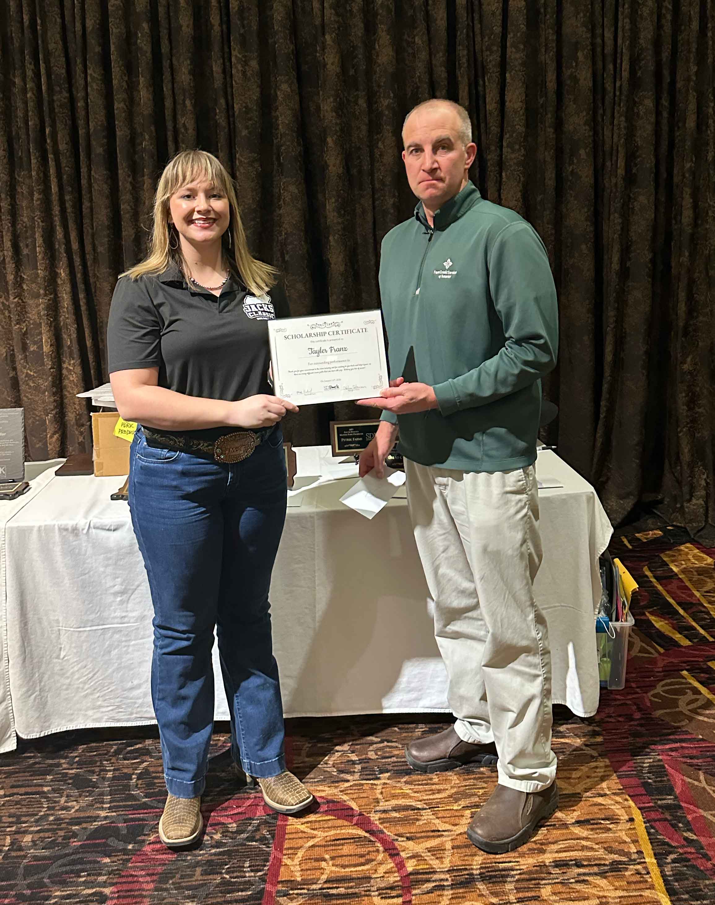 A girl in a grey T-shirt and jeans accepts a scholarship certificate